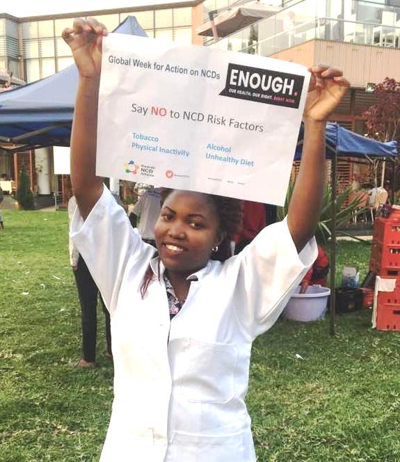 A member of Health Volunteers Initiative, Rwanda, holding up a sign celebrating the Global Week for Action on NCDs.