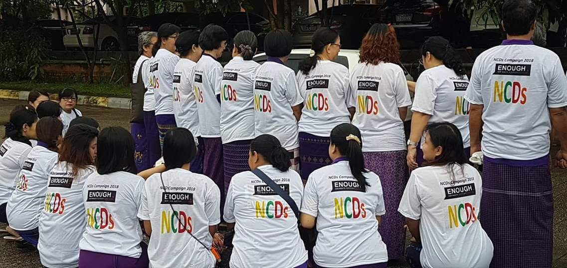 A dozen members of the Myanmar NCD Alliance wearing white T-shirts to mark the Global Week