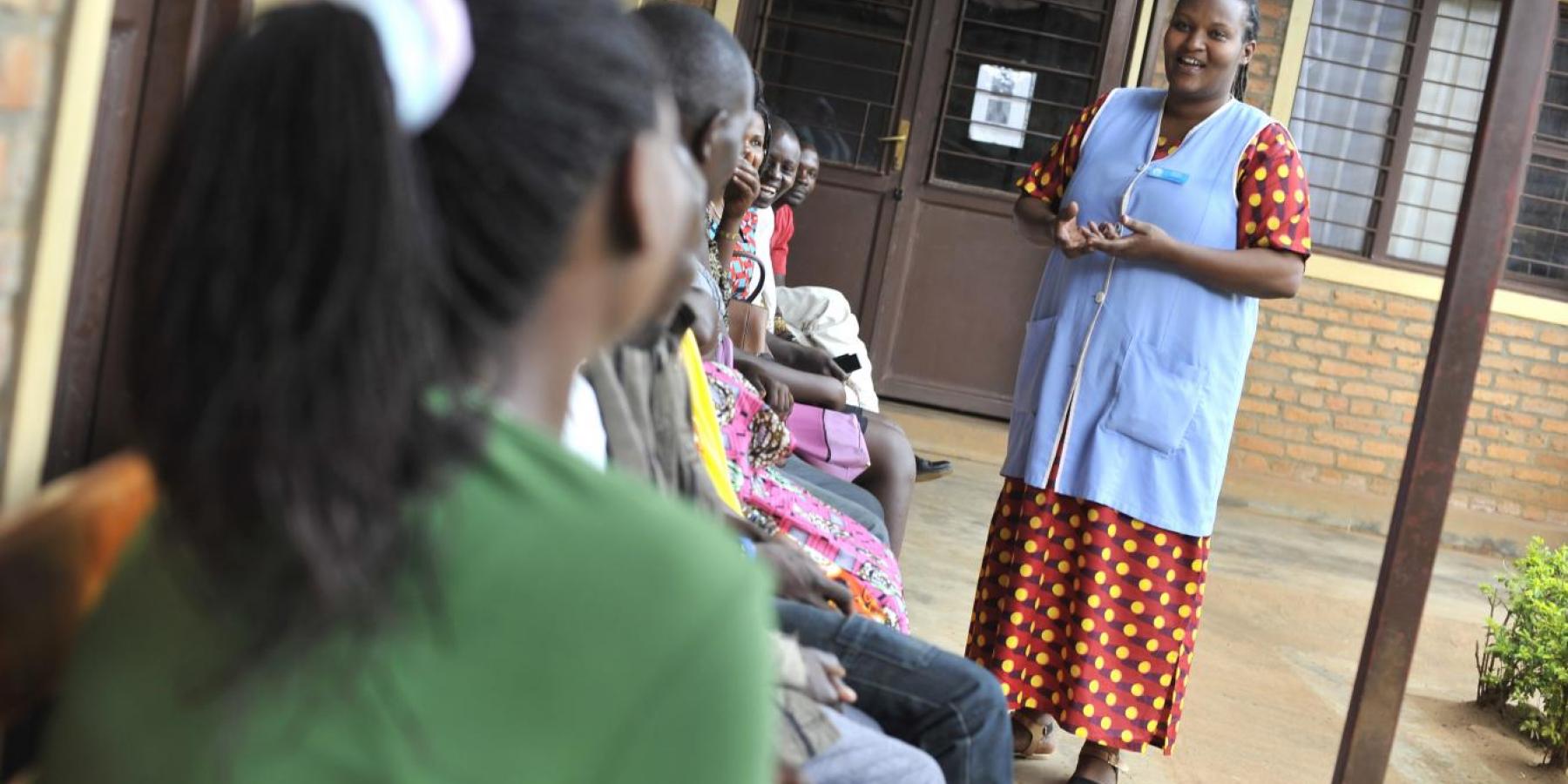 A health worker speaks to clients waiting for services at a clinic in Rwanda.