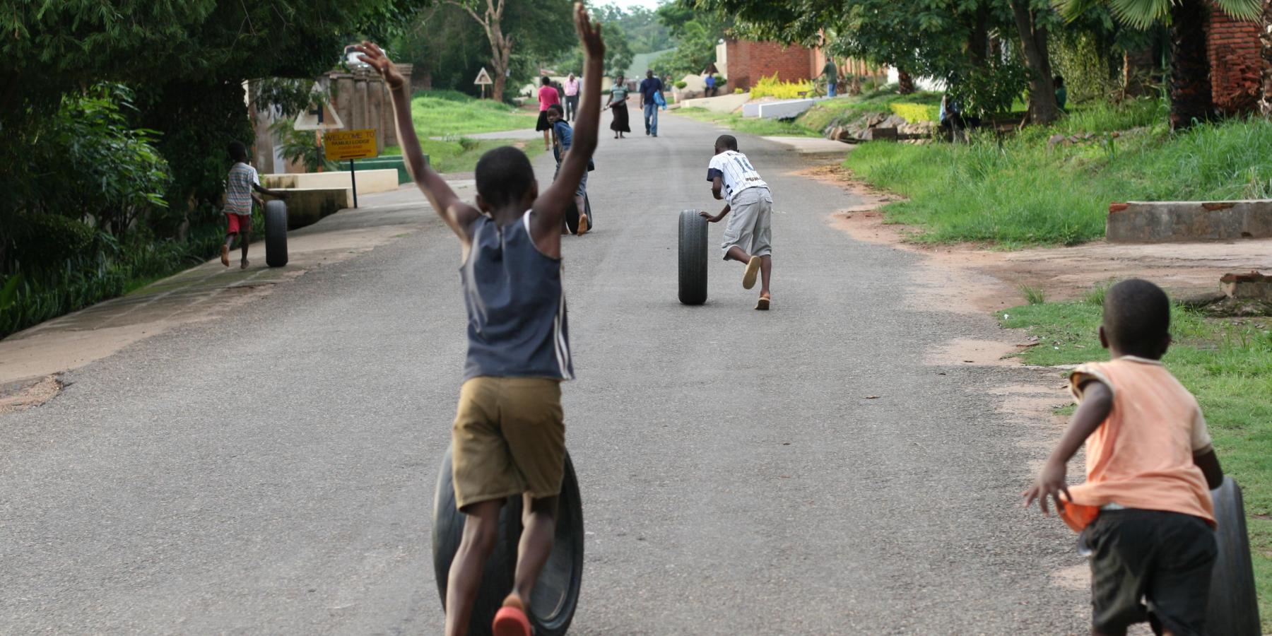 Children roll tires on a street in the Area 14 neighborhood of Lilongwe, Malawi